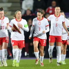 Piłkarki w biało-czerwonych strojach, dumny klub wybitnego reprezentanta, maszerują po murawie.