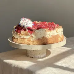Eine köstliche Sommer Torte mit Baiserhaube, roten Beeren und Mandelsplittern, verziert mit essbaren Blüten.