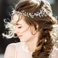 Une jeune femme avec une coiffure bohème, ornée d'une tiare scintillante, ses cheveux ondulés tombant en tresse.