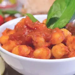 Gnocchi al pomodoro in una ciotola bianca, guarniti con basilico fresco. Un'idea su come condire gli gnocchi per un piatto saporito.