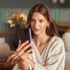 Kobieta z telefonem w ręku, szuka idealnego pomysłu na selfie.