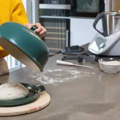 Préparation de la pâte à pizza avec un robot culinaire. Une boule de pâte repose sur un plat vert, prête à être cuite.
