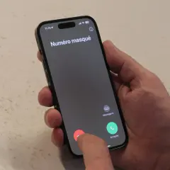 Un doigt touche le bouton rouge pour refuser un appel entrant "Numéro masqué", typique du démarchage téléphonique.