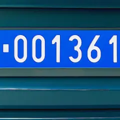 Niebieskie tablice rejestracyjne z numerem W-001361 na ciemnozielonym samochodzie.