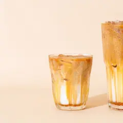 Zwei Eiskaffees: Ein kleinerer, der an einen Cappuccino erinnert, und ein größerer, der wie ein Latte Macchiato aussieht, mit Eis und Karamellsauce.