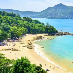 En solig dag på Laem Sing Beach med turkost vatten, grönskande kullar och besökare som njuter av sanden och havet.
