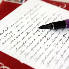 A purple fountain pen rests on a letter written in elegant cursive, demonstrating how to write it in cursive.