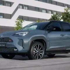 Szary Toyota Yaris Cross Hybrid GR Sport na tle nowoczesnego budynku.