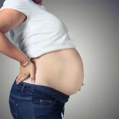 Kobieta w ciąży, z dłonią na plecach, zastanawia się, ile tygodni trwa ciąża.
