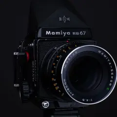 Czarny aparat Mamiya RB67 z obiektywem Mamiya-Sekor C f=180mm. Idealny do zdjęć, które wymagają precyzji i jakości, jaka klisza do aparatu jest w stanie zapewnić.