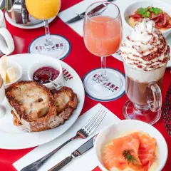 Un délicieux brunch avec enfants : toasts, œuf à la coque, confiture, jus d'orange, chocolat viennois et viennoiseries.