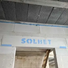 Piana montażowa w szczelinie między stropem a ścianą z bloczków z napisem "SOLBET".