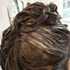 Dunkelbraunes Haar mit Farbauftrag, das auf die Einwirkzeit wartet. Wie lange muss Farbe beim Friseur einwirken?