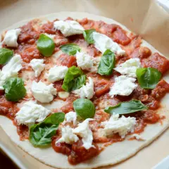 Pizza mozzarella z pomidorami i bazylią, gotowa do pieczenia.