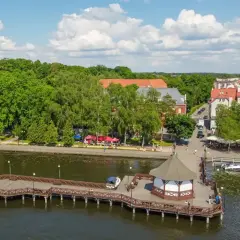 Idealny weekend na Mazurach: malownicza promenada, urokliwa przystań i uśmiechnięci ludzie cieszący się słońcem.
