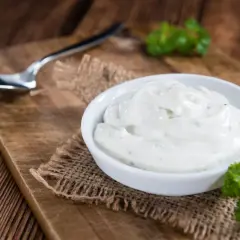 Cremige Sour Cream in einer Schale, bereit zum Dippen. Ein Löffel liegt daneben.
