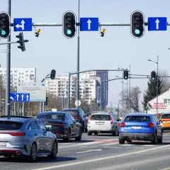 Na skrzyżowaniu z sygnalizacją świetlną, gdzie są kamery rejestrujące przejazd na czerwonym świetle, stoi kilka samochodów.