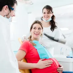 Uśmiechnięta ciężarna pacjentka u dentysty. Dbałość o zęby w ciąży to podstawa.