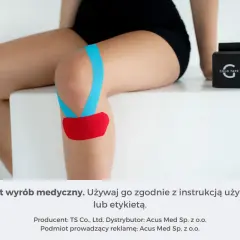 Kolorowe plastry fizjoterapeutyczne na kolanie, wspierające ruch. Obok pudełko z taśmą.