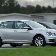 Silver tsi golf parkerad på en gräsmatta framför en vit byggnad.