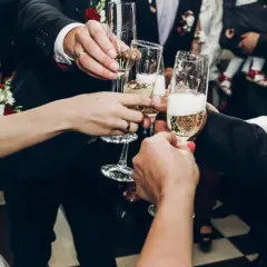 Para wznosi toast kieliszkami szampana. Zastanawiasz się, ile wódki na wesele? To zdjęcie nie odpowie, ale pokazuje radość!