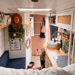 Ambiance chaleureuse et bohème pour ce deco interieur van. Un canapé bleu, des plantes grimpantes, un chapeau tendance et une cuisine fonctionnelle.