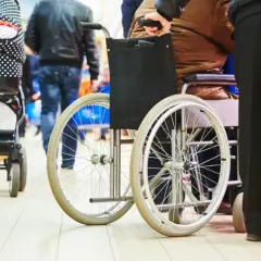 Opiekunowie osób niepełnosprawnych, wspierani przez 500 plus, poruszają się po sklepie. Wózek inwalidzki i spacerowy obok.