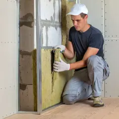 Operaio installa materiale isolante, creando un ambiente più silenzioso. Questo è il miglior isolante acustico per la tua casa.