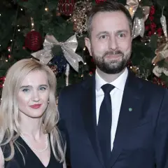 Para z uśmiechem na tle choinki.