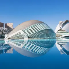 El Hemisfèric de Valencia, con su reflejo en el agua, se alza majestuoso bajo un cielo azul.