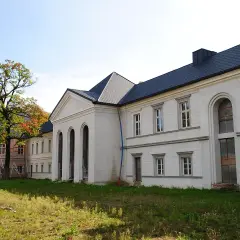 Pałac w Siemianowicach Śląskich, biała fasada z arkadowymi oknami i ciemnym dachem, otoczony zielenią i jesiennym drzewem.