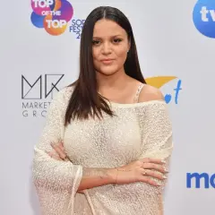 Dominika Gawęda z dzieckiem na ściance. Piosenkarka w błyszczącej bluzce.