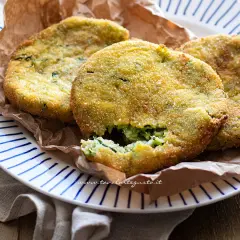 Crocchette di zucchine al forno, dorate e croccanti, servite su un piatto a righe blu.