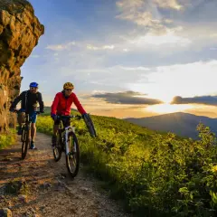 Dwóch rowerzystów na szlaku górskim podczas zachodu słońca. To idealny przykład turystyki rowerowej w Polsce.