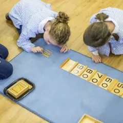 Niñas aprendiendo con el método Montessori en colegios, usando cuentas para sumar.