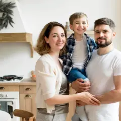 Uśmiechnięta rodzina: ojciec trzyma syna, matka obejmuje ich.