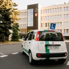 Biały Fiat Panda z zielonym pasem i literą "L" na dachu, gotowy do nauki jazdy. To auto jest kluczowe, gdy zastanawiasz się, co jest potrzebne do odbioru prawa jazdy.