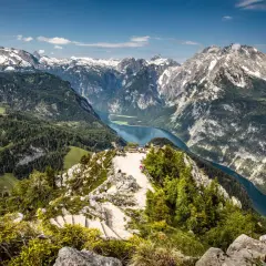 Atemberaubender Blick über den Königssee und die Berchtesgadener Alpen. Ein Aussichtspunkt mit Menschen lädt zum Verweilen ein.