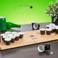 En rolig lekar fest vuxna inomhus med beer pong-spel. En boll flyger mot muggarna på träplattan.