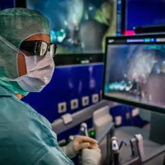 Chirurg in OP-Kleidung blickt auf Monitor, der eine Operation zeigt. Ziel: besserer Stoffwechsel nach Gallen-OP.