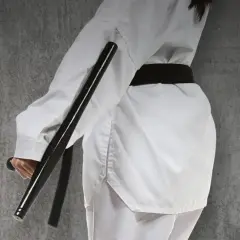 Osoba w białym stroju do sztuk walki trzyma pałkę tonfa.