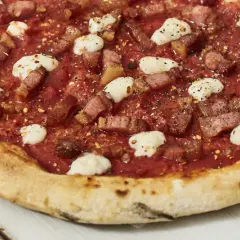 Pizza con guanciale croccante, pomodoro e fiocchi di pecorino, un sapore intenso e autentico.