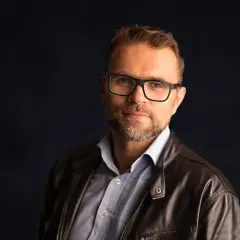 Jacek Bartosiak w skórzanej kurtce i okularach, autor inspirujących książek.