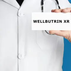 Lekarz w białym kitlu prezentuje kartkę z napisem WELLBUTRIN XR.
