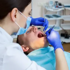 Dentystka bada zęby pacjenta. Czy dentysta może wystawić L4? Tak, jeśli stan zdrowia pacjenta tego wymaga.
