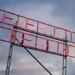 Insegna al neon rosa con la scritta "NEVER STOP DREAMING". Un promemoria ispiratore, come frasi sulla rinascita in inglese, per non smettere mai di sognare.