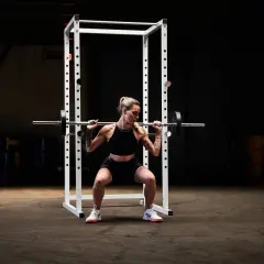 Kvinna utför squats med stång i ett gym.