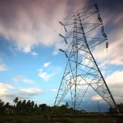 Wieża energetyczna na tle nieba z chmurami. Linie energetyczne, jak taryfa G13, łączą krajobraz.