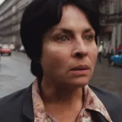 Kobieta samotna film. Zamyślona twarz kobiety na tle ulicy z samochodami i budynkami.