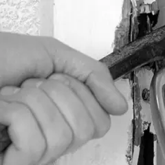 Mano con cincel forzando una puerta, una imagen que evoca la problemática de los okupas en España.